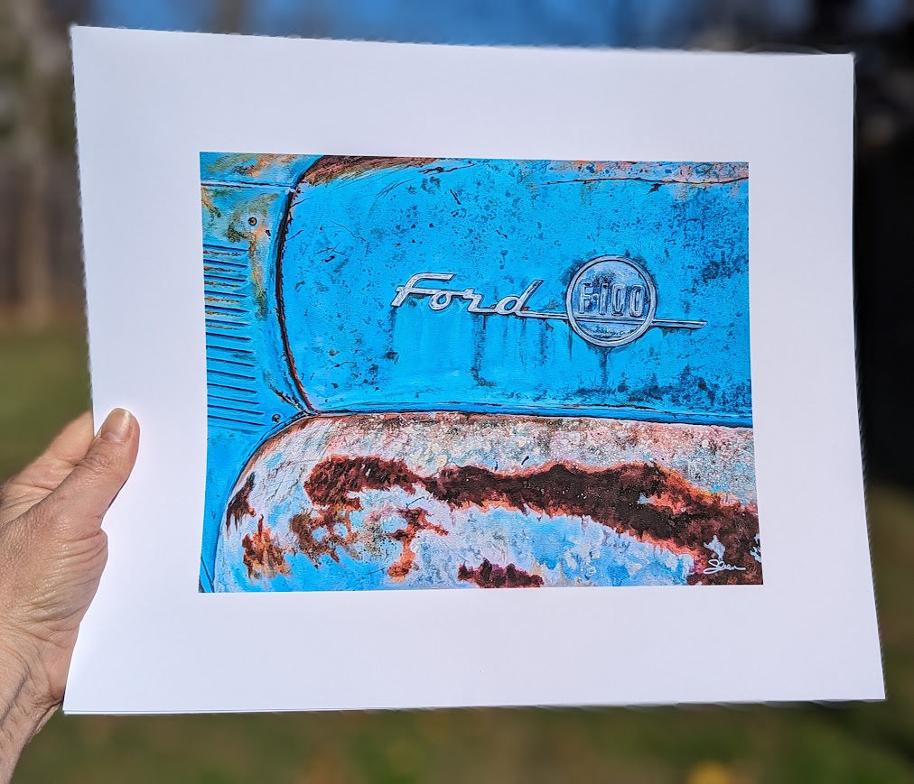 A person proudly displaying a limited edition Shan Fannin "Barn Find (Ford F100)" blue print, reminiscent of a barn find.