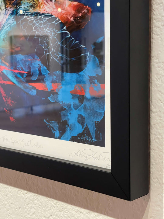 Close-up of a framed Lindsey Kustusch limited edition print, "The Green Sea Turtle," featuring abstract blue and red patterns with the artist's signature and title on the white border.