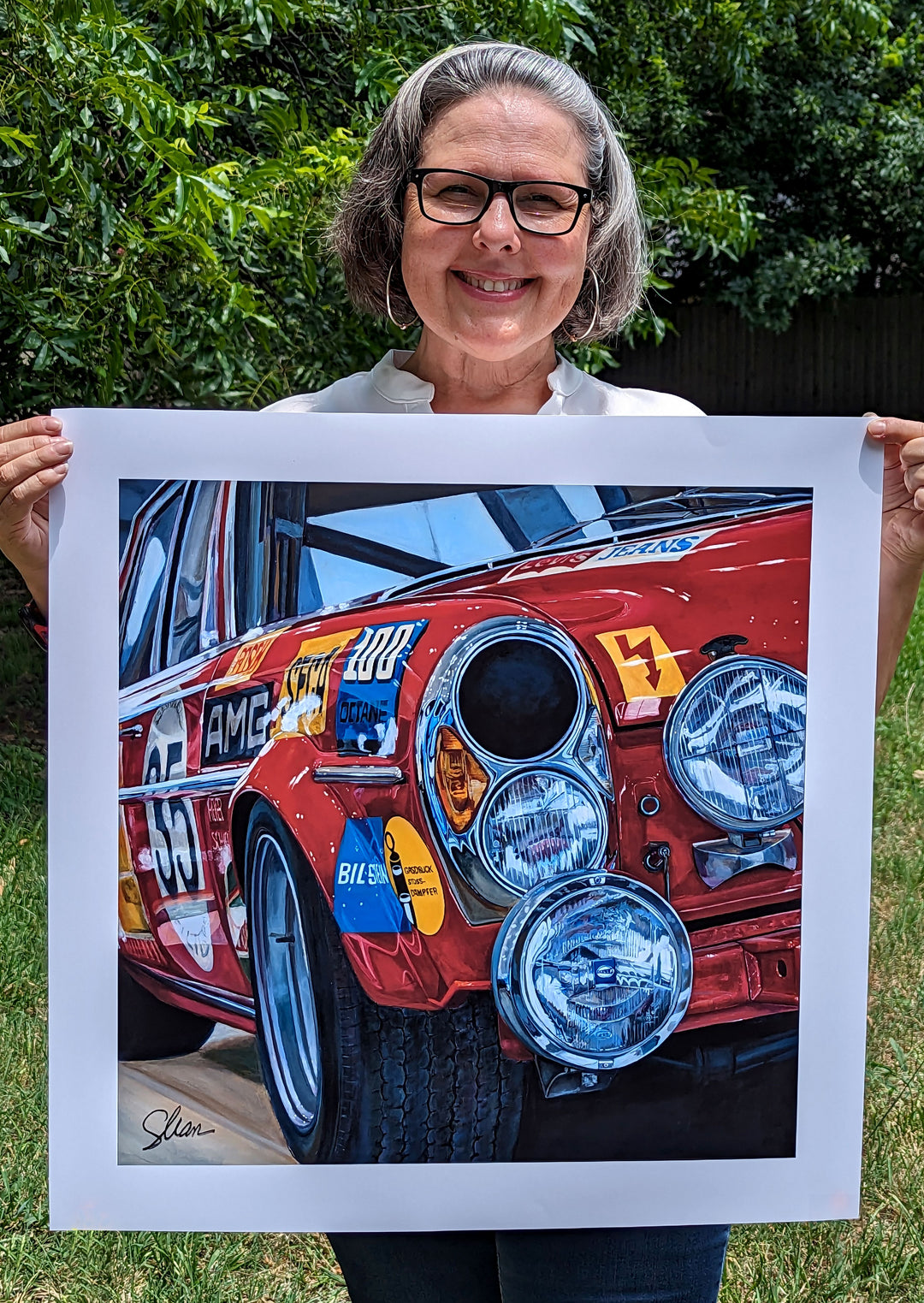 A woman holding up a Shan Fannin | "1971 Mercedes AMG 300 SEL (a.k.a. 'Red Pig')" | 28 x 28" painting.
