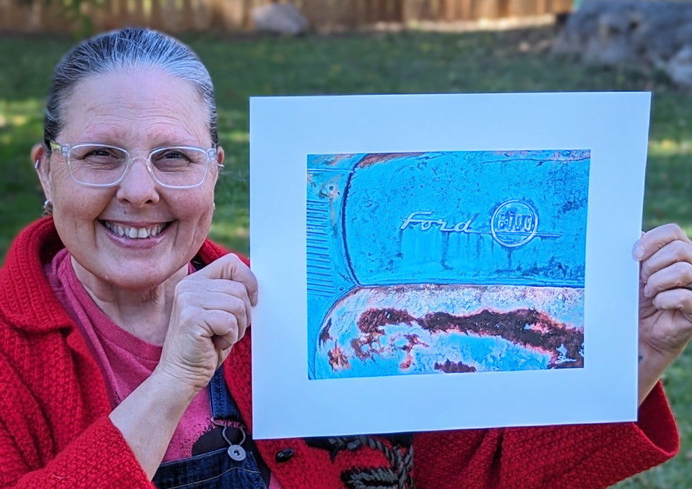 A woman proudly displaying a limited edition giclée print of "Barn Find (Ford F100)" by Shan Fannin.