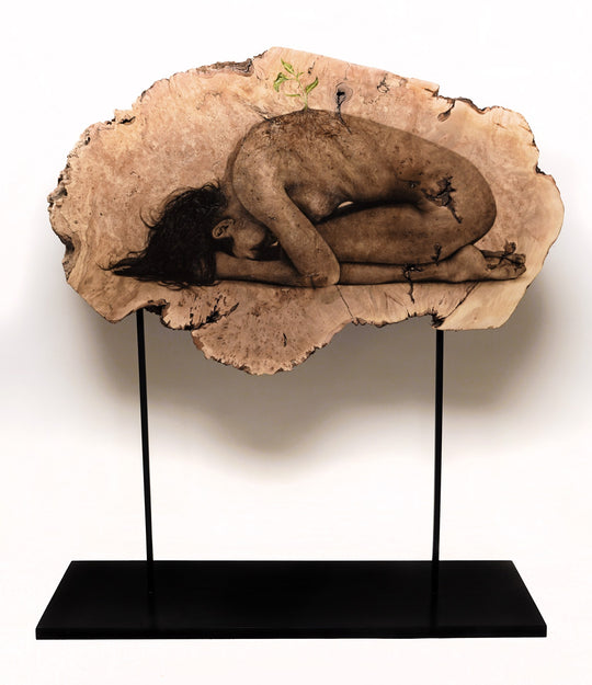 A sculpture of a woman laying on a piece of wood, depicting the beautiful process of Oda & King - "Rebirth".
