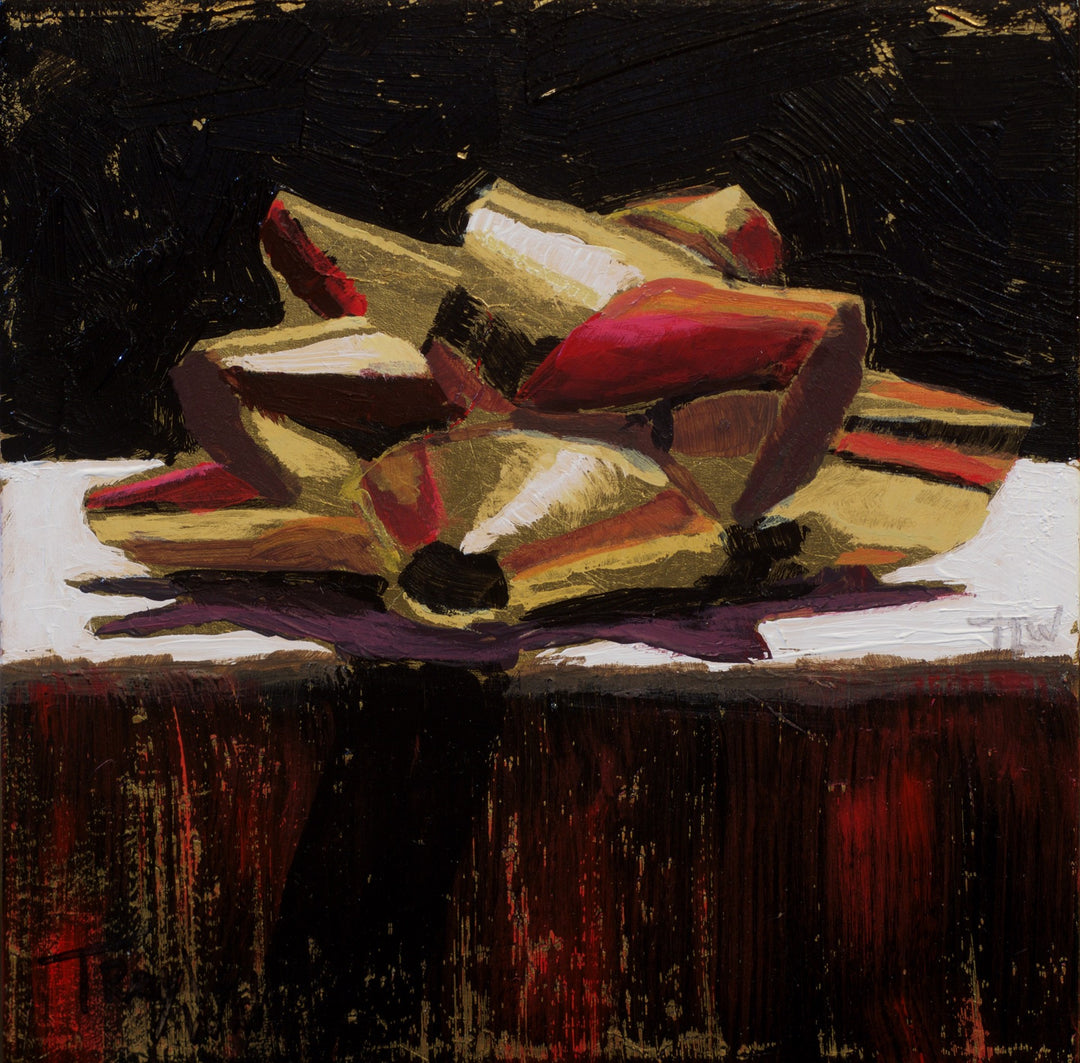 A mixed media painting by Tracy Wall featuring a red and gold bow, titled "Tracy Wall - Gift of Gold", displayed on a table.